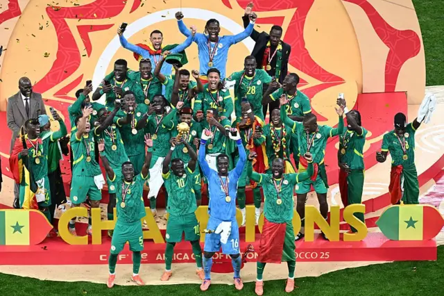 يحتفل لاعبو المنتخب السنغالي بفوزهم بلقب كأس الأمم الأفريقية، وهم يرتدون قمصان وسراويل وجوارب خضراء، باستثناء حارس المرمى إدوارد ميندي الذي يرتدي تيشيرت وشورت وجوارب زرقاء. ويرتدي اللاعبون السنغاليون، بقيادة نجم الفريق ساديو ماني، الميداليات الذهبية ويحملون كأس البطولة.