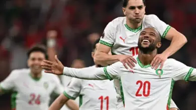 صورة للاعب منتخب مغربي وهو يقفز على أكتاف زملائه في الملعب أثناء احتفاله بتسجيل الهدف الثاني في مباراة المغرب وزامبيا التي انتهت بفوز المغرب 3-0.